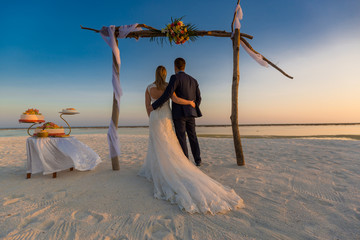 Fototapeta na wymiar Beautiful beach wedding arch during sunset. Married couple enjoying life