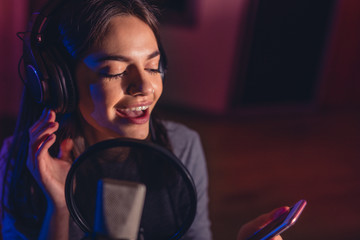 Female singing a sing with mobile phone at recording studio