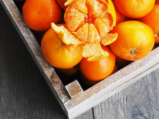 Fresh tangerines in an old box with leaves. On wooden background. Top view
