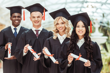 group of multiethnic students with diplomas
