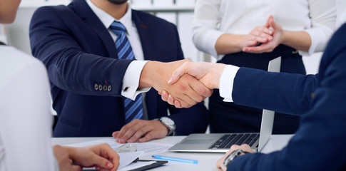Business handshake at meeting or negotiation in the office, close-up. Partners are satisfied because signing contract or financial papers
