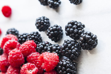 Fresh raspberries and blackberries on marble table, selective focus