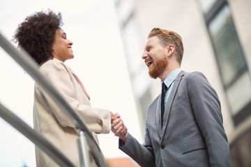 Happy business people shaking hands on city street