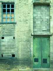 Fotobehang Pistache verwaarloosd en verlaten industrieel magazijn en fabrieksgebouw met dichtgemetselde ramen en groene deur in Halifax, Yorkshire in Groot-Brittannië