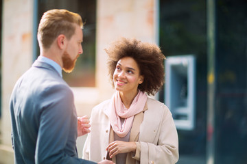 Two business people in an informal conversation in front of a business building