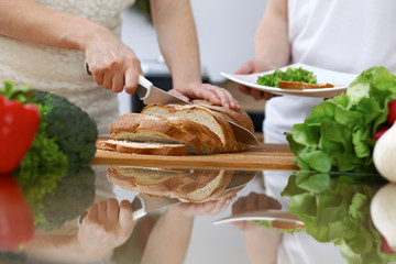Close-up of human hands slicing bread in a kitchen. Friends having fun while cooking in the kitchen. Chef cook represent culinary masterclass
