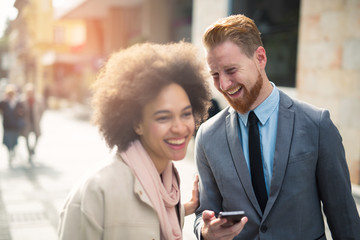 Happy business couple using smart phone outdoors