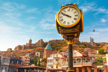 Fototapeta na wymiar Amazing view of City clock, Old Meidan Square and Narikala ancient fortress in the sunny morning, Tbilisi, Georgia.