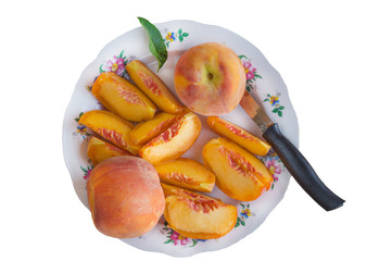 Ripe peaches with slices and knife  in a ceramic plate isolated on white background