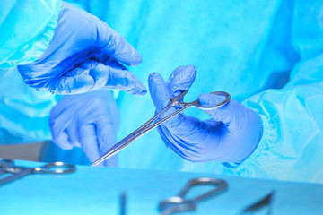 Close-up of of surgeons hands at work in operating theater toned in blue