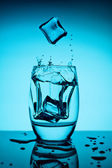 Water splash in glass with ice cubes