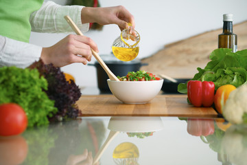 Closeup of human hands cooking vegetables salad in kitchen on the glass  table with reflection