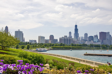 Modern architecture and urban background. Cloudy sky over Chicago downtown skyline, lake Michigan marina and bright blooming flowers on a foreground. Chicago, Illinois, Midwest USA. Horizontal view.