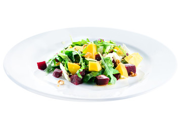 Delicious and appetizing salad with beetroot and fruit mango in a white plate isolated on white background. Autumn menu in an Italian restaurant. Photo for menu design