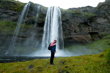 Adventure man by skogafoss waterfall, nature on Iceland. Young man visiting nature landscape.