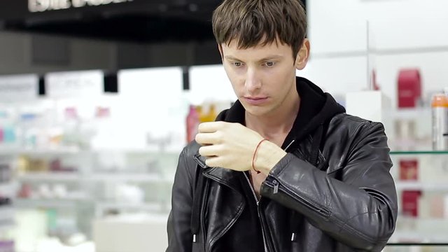 Young handsome man choosing perfume in boutique. close-up