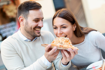 Couple eating pizza snack outdoors.They are sharing pizza and eating.