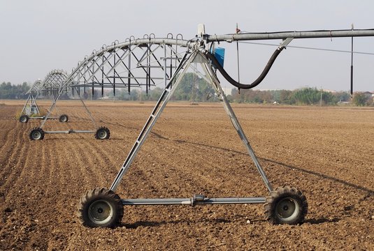 Center pivot irrigation system in a plowed field on a sunny day