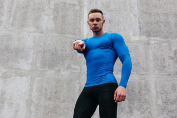 Portrait of a sporty young man in a blue T-shirt in gray wall background