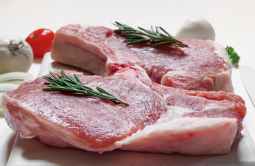 Raw ribeye pork steaks on white painted cutting board