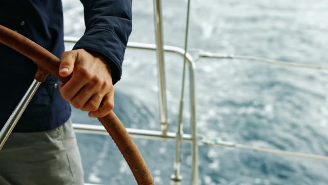 Man holding steering wheel. Controlling a yacht