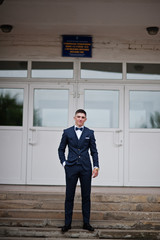 Portrait of a handsome high school graduate in stylish tuxedo posing on the stairs on the prom. © AS Photo Family