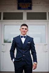 Portrait of a handsome high school graduate in stylish tuxedo posing on the stairs on the prom. - obrazy, fototapety, plakaty