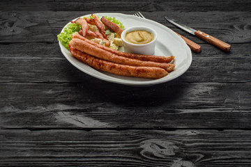 Grilled sausages over dark wooden background.
