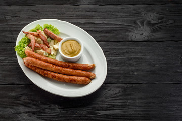 Grilled sausages over dark wooden background.