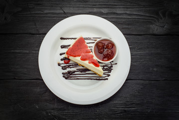 Delicious cheesecake with berries on a white plate over dark wooden background
