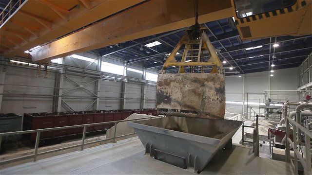 Work on the bridge crane stock granulation of bulk materials, Warehouses for bulk materials, Grab crane loads raw materials, crane bucket, Modern factory, interior