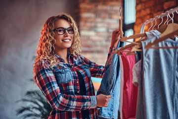 Fototapeta premium A woman chooses fashionable clothes on the coat rack.