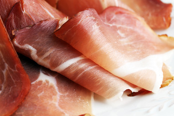 Italian prosciutto crudo or jamon. Raw ham on white dish.