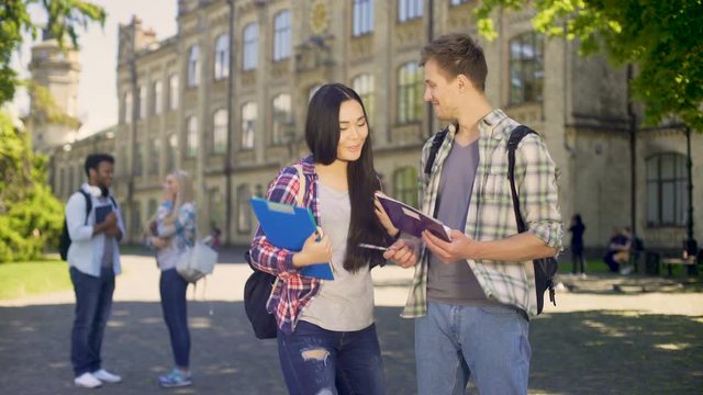 Male student helping his biracial classmate with homework, explaining details