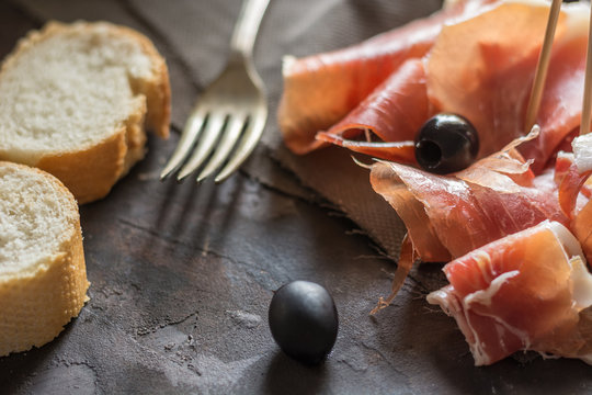 Portion of Ib&eacute;ric ham, along with bread and olives.
