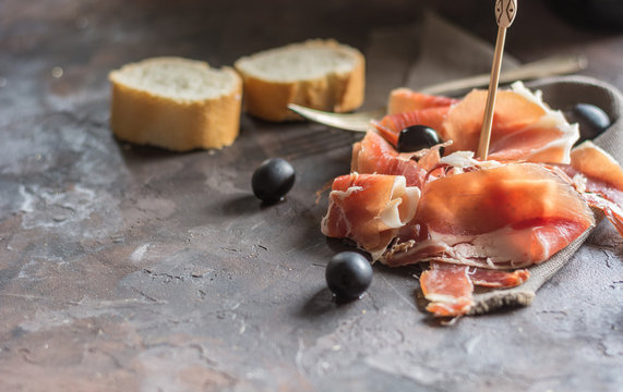 Portion of Ib&eacute;ric ham, along with bread and olives.
