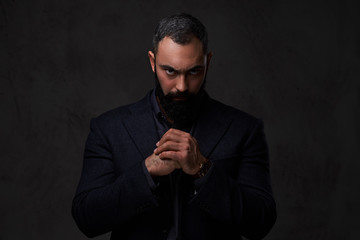 Serious, bearded male dressed in a grey suit.