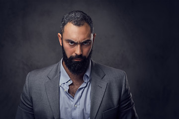 Serious, bearded male dressed in a suit.