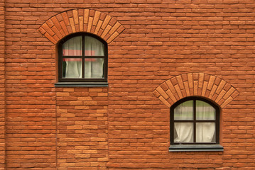 wall of an old red brick building with two window