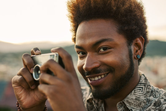 Young black man holding an old camera at sunset.