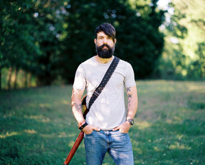 Portrait of a bearded man with a guitar on his back