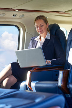 Businesswoman Working On Laptop In Helicopter Cabin During Flight