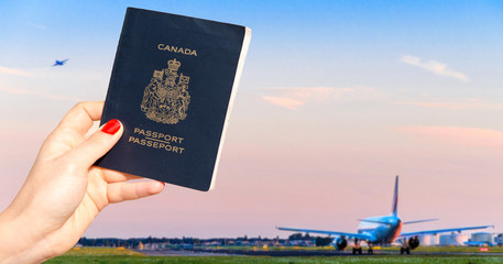 Person holding a Canadian passport with one airplane taxiing and another taking off - travel concept - obrazy, fototapety, plakaty