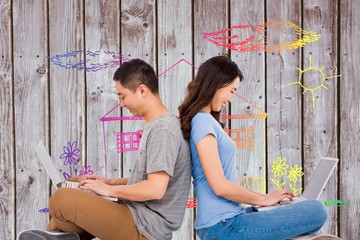 Composite image of happy young couple using laptop while sitting
