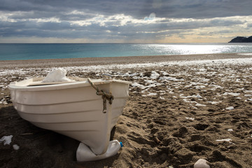 A boat under the snow on the beach