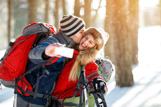 Young skiers kissing while making selfie