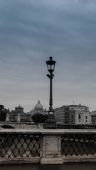 Fototapeta na wymiar view of the lantern bridge standing on the bridge, Tybr, the bridge and the Basilica of St. Peter in black and white colors with a hazy sky