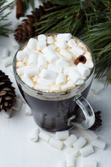 mug with hot coffee drink or chocolate with marshmallow, close-up on a white background, spruce branches, cones, christmas toys close-up.