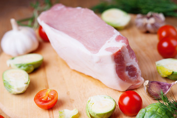 Raw pork on cutting board and vegetables 