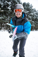 Fototapeta na wymiar Attractive man holding snowboard and going to freeride to the mountain
